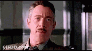 A Man With A Mustache And A Suit And Tie Is Making A Funny Face . GIF