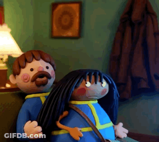 A Man With A Mustache And A Woman With Long Black Hair Are Sitting On A Couch GIF