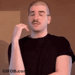 A Man With A Mustache And Glasses Is Wearing A Black Shirt And Making A Funny Face . GIF