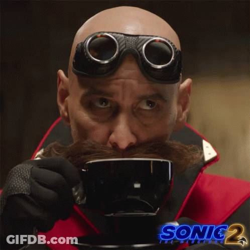 A Man With A Mustache And Goggles Is Drinking From A Cup With Sonic 2 Written On The Bottom GIF