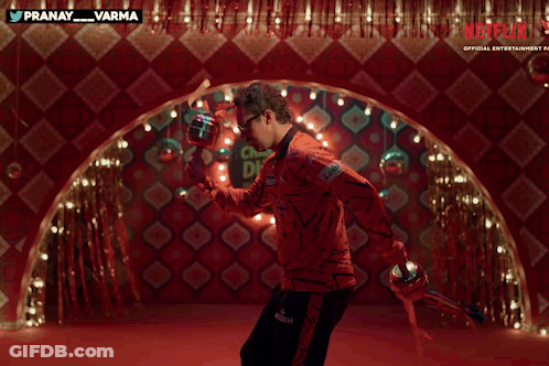A Man With A Mustache And Sunglasses Is Dancing In Front Of A Red Wall With Netflix Written On It GIF