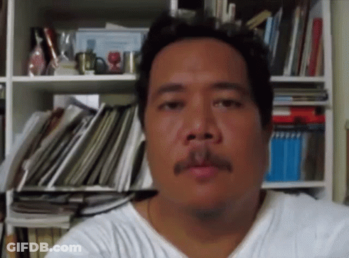A Man With A Mustache In Front Of A Bookshelf Full Of Books GIF