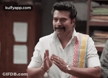 A Man With A Mustache Is Clapping His Hands While Wearing A White Shirt . GIF