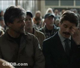A Man With A Mustache Is Covering His Eyes In A Crowd GIF