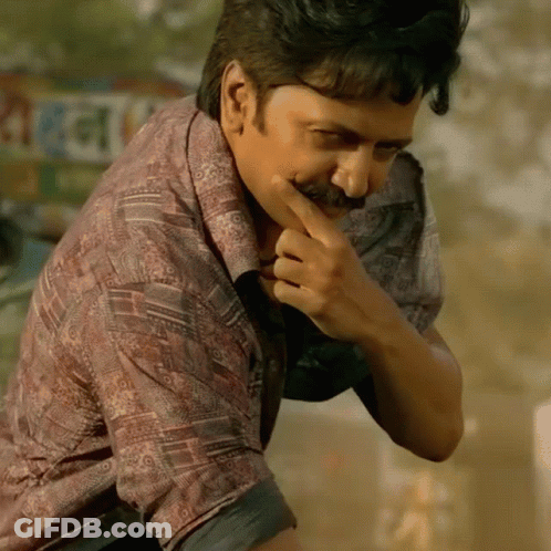 A Man With A Mustache Is Covering His Mouth With His Hand In Front Of A Sign That Says ' Rani ' GIF