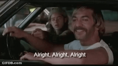 A Man With A Mustache Is Driving A Car With Another Man Sitting In The Back Seat . GIF