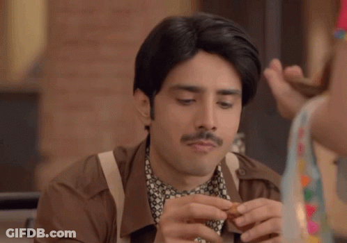 A Man With A Mustache Is Eating A Snack GIF