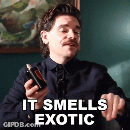 A Man With A Mustache Is Holding A Bottle Of Perfume And Says It Smells Exotic GIF