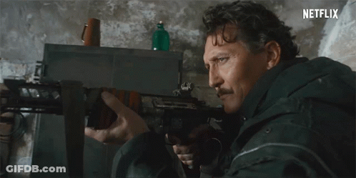 Man With Mustache Holding Rifle In Front Of Netflix Sign GIF