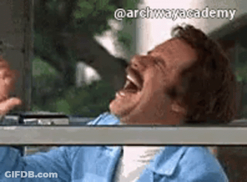 A Man With A Mustache Is Laughing With His Mouth Open While Sitting In A Car . GIF