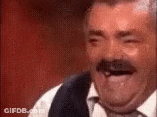 A Man With A Mustache Is Laughing With His Tongue Out While Wearing A Vest And Tie . GIF