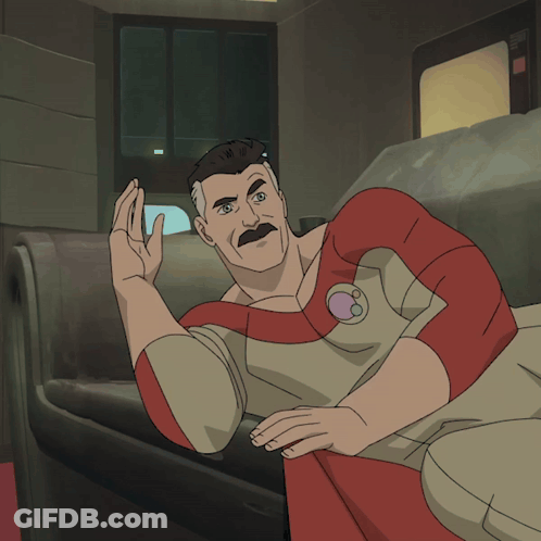 A Man With A Mustache Is Laying On A Couch And Waving GIF