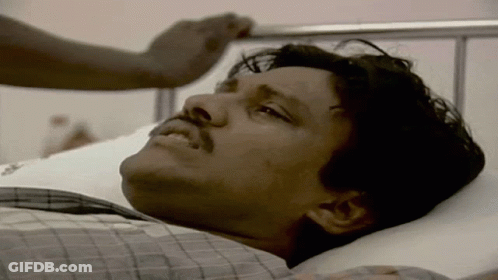 A Man With A Mustache Is Laying On A Hospital Bed GIF