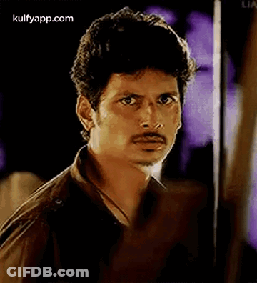 A Man With A Mustache Is Looking At The Camera . GIF