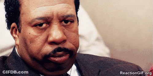 A Man With A Mustache Is Looking At The Camera With A Reactiongif.org Watermark GIF