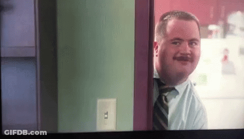 A Man With A Mustache Is Looking Through A Doorway GIF