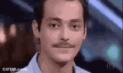 A Man With A Mustache Is Making A Funny Face While Looking At The Camera . GIF
