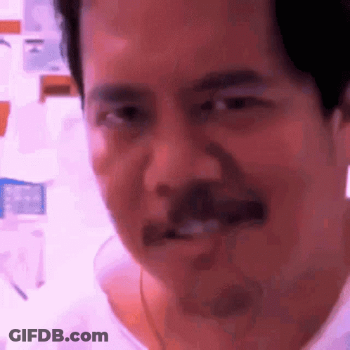 A Man With A Mustache Is Making A Funny Face While Looking At The Camera . GIF