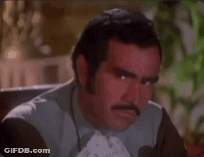 A Man With A Mustache Is Making A Funny Face While Sitting Down . GIF