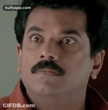 A Man With A Mustache Is Making A Funny Face With His Eyes Wide Open . GIF