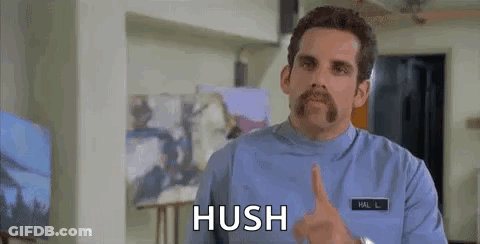 A Man With A Mustache Is Making A Hush Gesture With His Finger To His Mouth . GIF