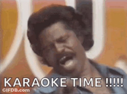 A Man With A Mustache Is Singing Into A Microphone With The Words `` Karaoke Time !!! '' Written Below Him . GIF