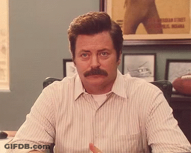 A Man With A Mustache Is Sitting At A Desk In Front Of A Framed Picture Of A Football Player .. GIF
