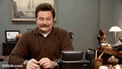 A Man With A Mustache Is Sitting At A Desk GIF