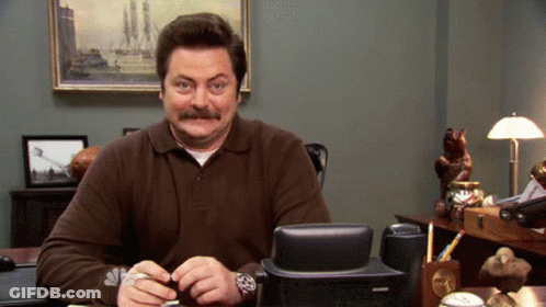 A Man With A Mustache Is Sitting At A Desk With A Nbc Logo On His Watch GIF