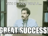 A Man With A Mustache Is Sitting At A Desk With The Words `` Great Success '' Written On It . GIF
