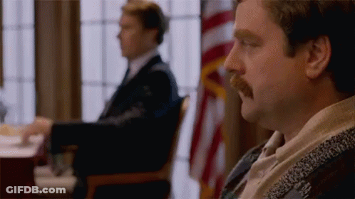 A Man With A Mustache Is Sitting At A Table In Front Of A Window . GIF