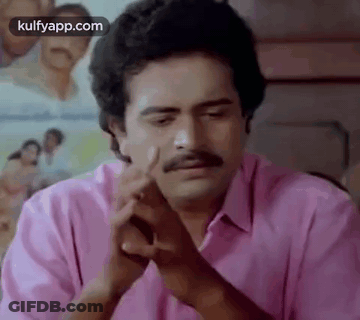A Man With A Mustache Is Sitting At A Table With His Hands Folded In Front Of Him . GIF