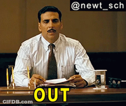 A Man With A Mustache Is Sitting At A Table With The Word Out On The Table GIF