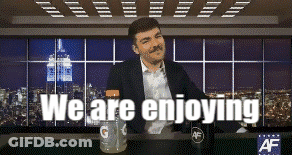 A Man With A Mustache Is Sitting At A Table With The Words " We Are Enjoying " Above Him GIF
