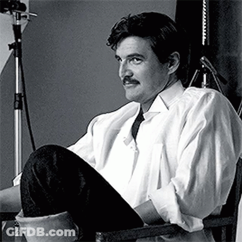 A Man With A Mustache Is Sitting In A Chair In Front Of A Microphone . GIF