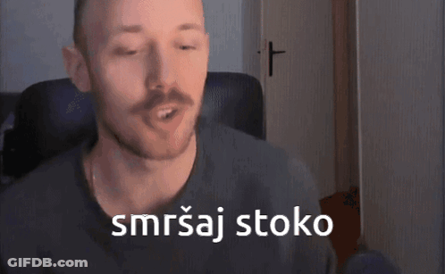 A Man With A Mustache Is Sitting In A Chair With A Cross In The Background And Says Smrtaj Stoko GIF