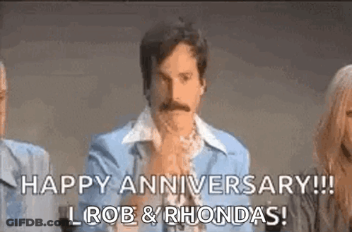 A Man With A Mustache Is Sitting In Front Of A Group Of People And Says `` Happy Anniversary ! `` GIF