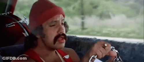A Man With A Mustache Is Sitting In The Driver 'S Seat Of A Car Holding A Key . GIF