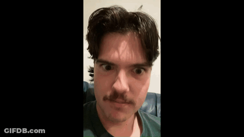 A Man With A Mustache Is Sitting On A Couch . GIF