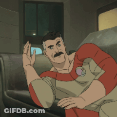 A Man With A Mustache Is Sitting On A Couch And Waving GIF