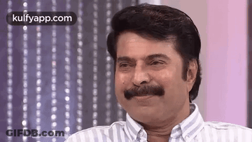 A Man With A Mustache Is Smiling And Looking At The Camera . GIF