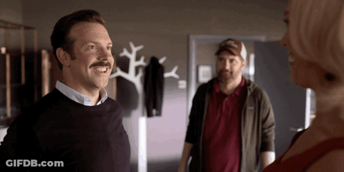 A Man With A Mustache Is Smiling In Front Of A Woman GIF