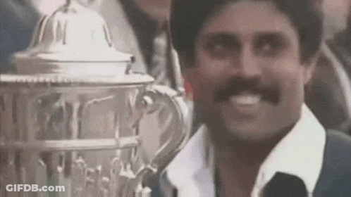 A Man With A Mustache Is Smiling While Holding A Trophy In Front Of Him . GIF