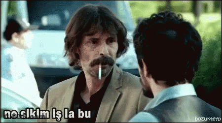 A Man With A Mustache Is Smoking A Cigarette And Talking To Another Man GIF