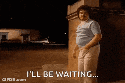 A Man With A Mustache Is Standing In Front Of A Building And Saying I 'Ll Be Waiting GIF