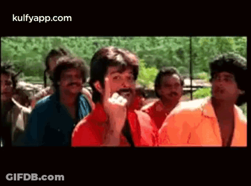 A Man With A Mustache Is Standing In Front Of A Crowd Of Men . GIF