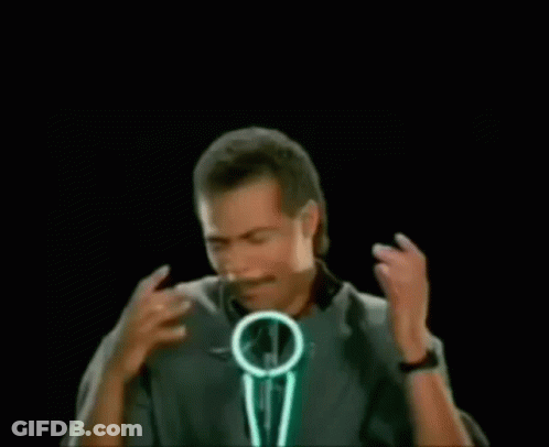 A Man With A Mustache Is Standing In Front Of A Microphone With The Words Bustin ' Makes Me In Green Letters . GIF