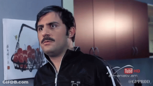 A Man With A Mustache Is Standing In Front Of A Painting That Says Tube Hd GIF