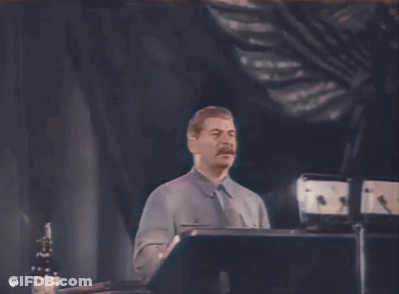 A Man With A Mustache Is Standing In Front Of A Podium . GIF