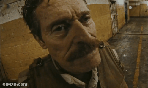 A Man With A Mustache Is Standing In Front Of A Yellow Wall GIF
